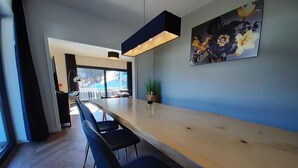 A modern dining area with a long wooden table, black chairs, and a large window offering a view of the outdoors. - Villa in Winterberg Near the ski Area (Winterberg)