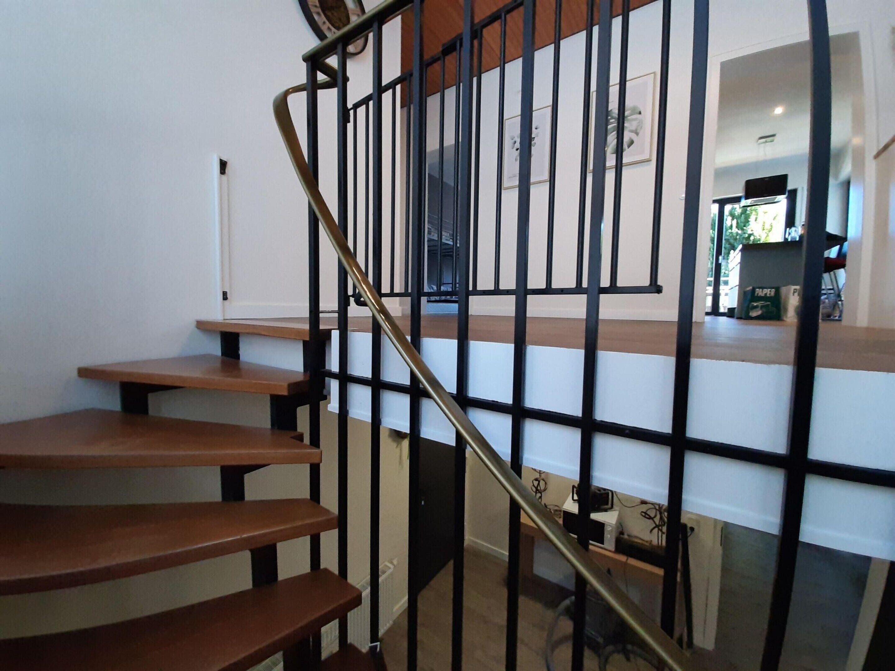 Una escalera de madera con barandillas de metal negro que conduce a una plataforma.