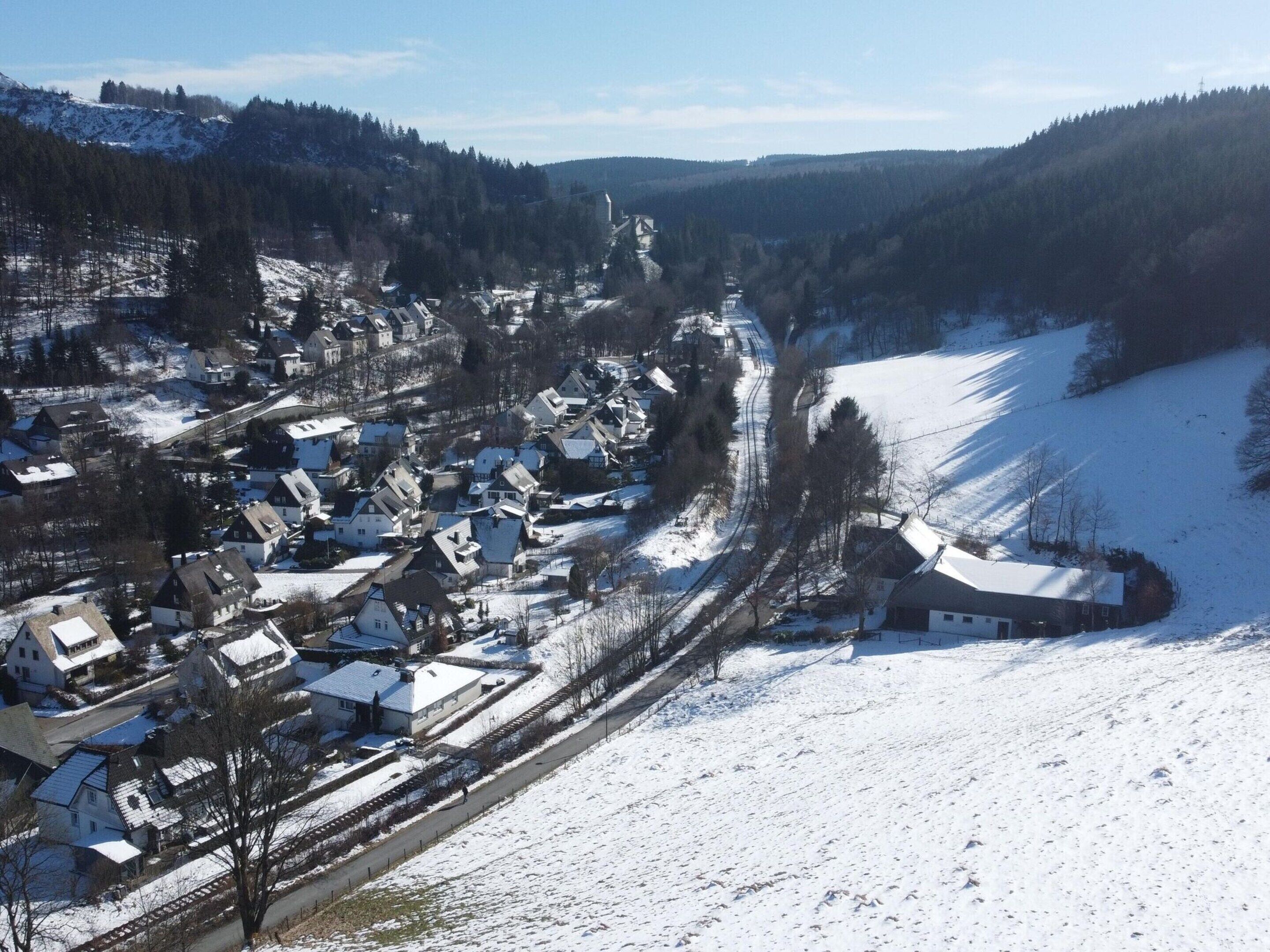A snow-covered village with houses and a railway track.
