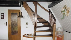 A wooden staircase with a dark finish, a wooden door with a decorative panel, and a small wooden bench. - in the Achtern Diek Holiday Park (Butjadingen)
