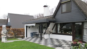 A house with a checkered patio, a blue bench, and a birdhouse. - in the Achtern Diek Holiday Park (Butjadingen)