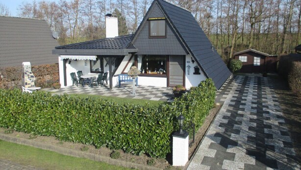 A house with a sloped roof, a covered patio with outdoor furniture, and a checkered driveway. - in the Achtern Diek Holiday Park (Butjadingen)