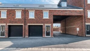 A multi-story brick building with a garage entrance and two closed garage doors. - Bridge House in Skinningrove (Saltburn-by-the-Sea)
