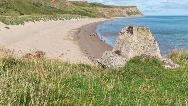 A coastal landscape with a sandy beach, grassy hills, and a clear sky. - Bridge House in Skinningrove (Saltburn-by-the-Sea)