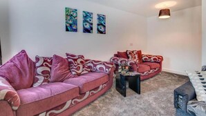 A living room with two sofas, a coffee table, and three wall-mounted paintings. - Bridge House in Skinningrove (Saltburn-by-the-Sea)