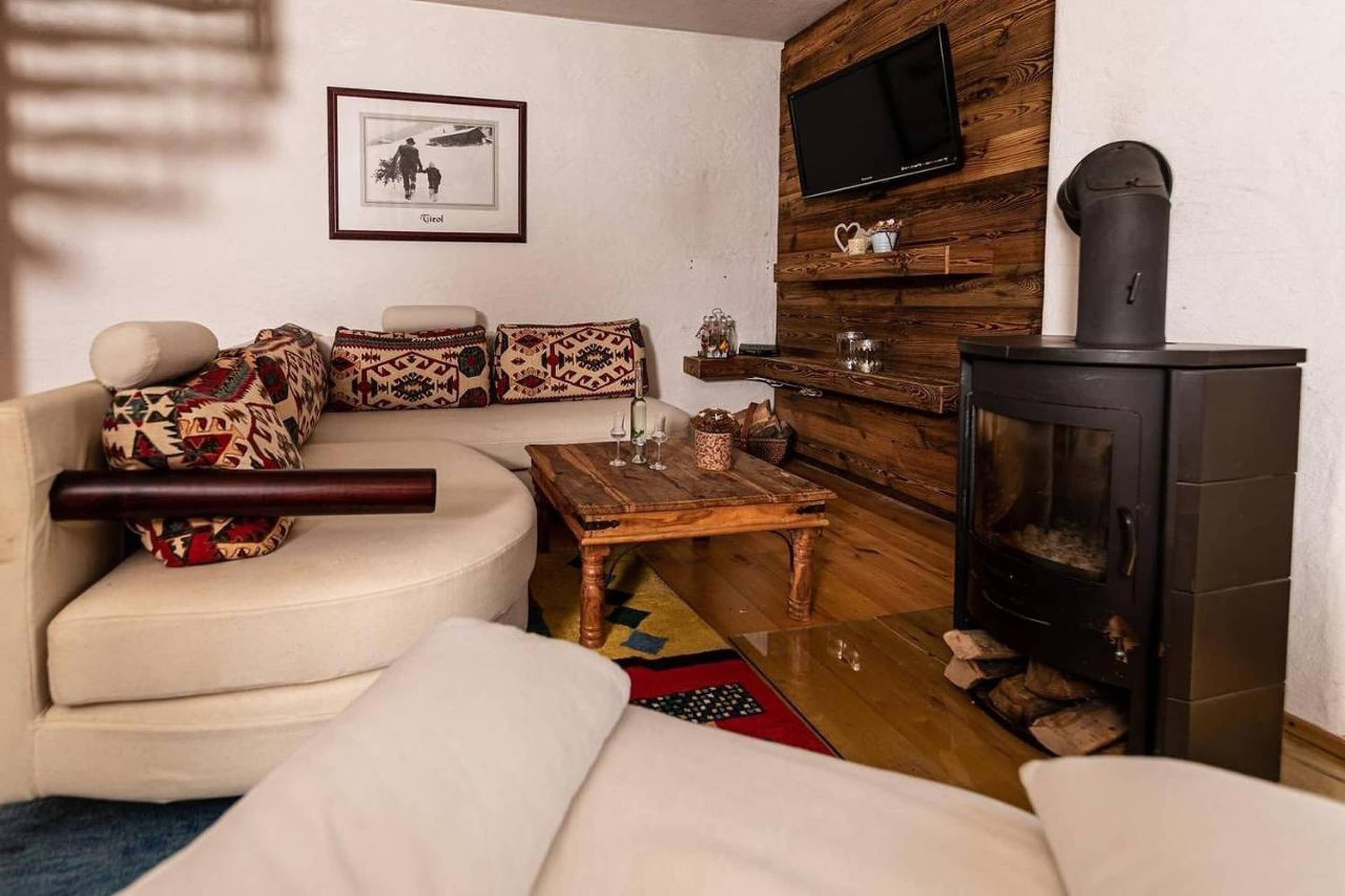 A living room with a sofa, a coffee table, a fireplace, a TV mounted on a wooden wall, and a framed picture on the wall.