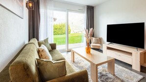 A modern living room with a sofa, coffee table, and TV. - Apartment in Ellmau With Ski-in Access (Ellmau)