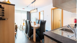 A modern kitchen with a dining area, wooden cabinets, and a built-in sink. - Apartment in Ellmau With Ski-in Access (Ellmau)