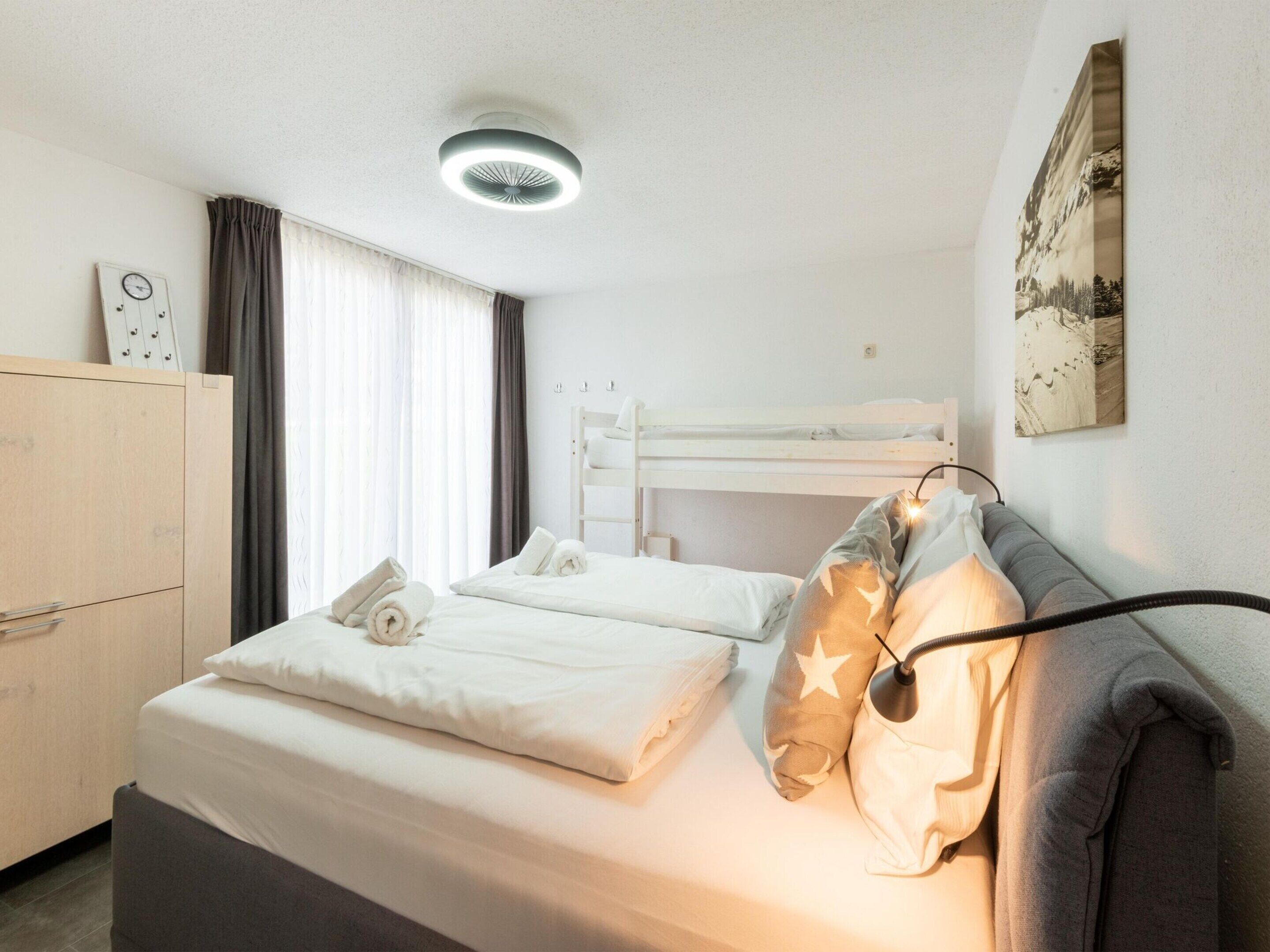 Una habitación de hotel con literas, una mesita de noche, un armario y una obra de arte colgada en la pared.