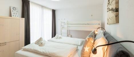 Hotellihuone, jossa on kerrossänky, yöpöytä, vaatekaappi ja seinälle ripustettu taideteos.