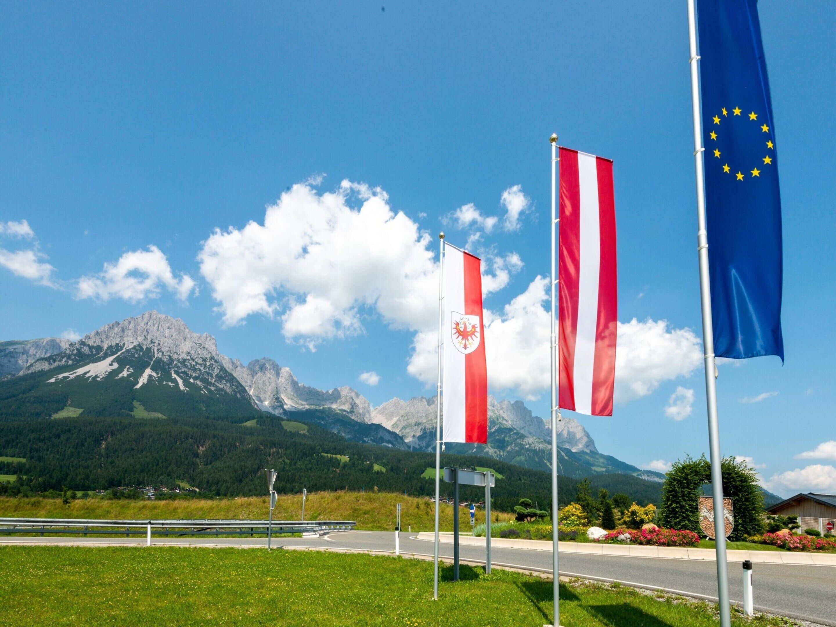 A road with flags, a mountain range, and a clear sky.