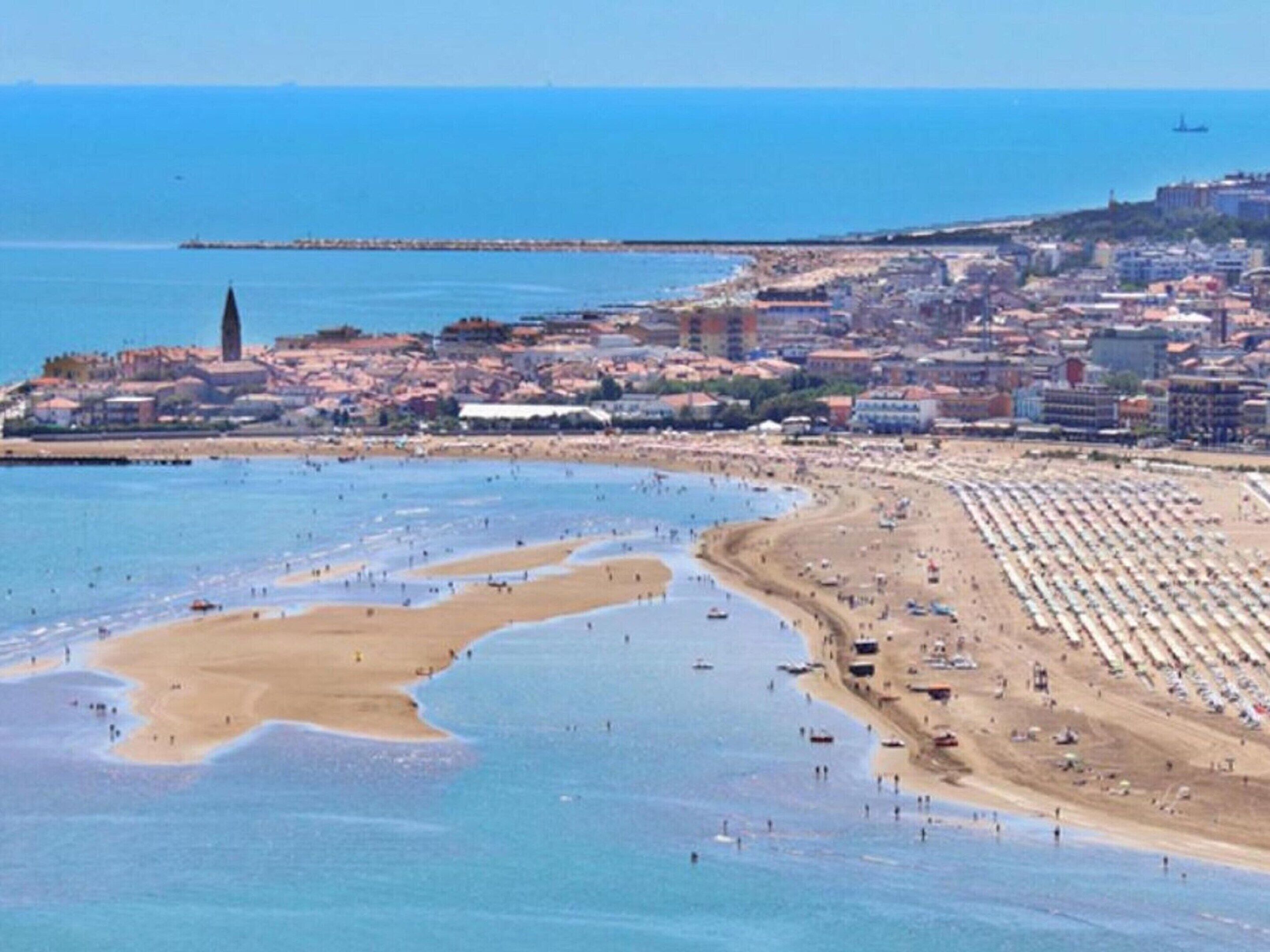 Eine Küstenstadt mit Strand, Gebäuden und einem Leuchtturm.