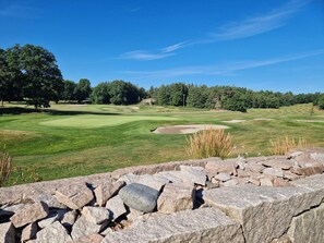 A golf course with a stone wall in the foreground, trees in the background, and a clear blue sky. - 4 Star Holiday Home in Tanumshede (Tanum)