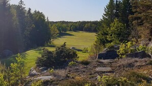 Ein Golfplatz, umgeben von dichtem Wald und felsigem Gelände.