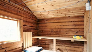A wooden cabin interior with a window, a bench, and shelves. - Holiday Home by the Lake (Tived)
