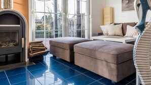 A modern living room with a fireplace, a sofa set, and a large window with a view of the outdoors. - Seahorse Modern Retreat (Ostseebad Ahrenshoop)