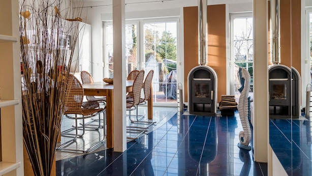 A modern interior with a dining area, two fireplaces, and a large window providing natural light. - Seahorse Modern Retreat (Ostseebad Ahrenshoop)