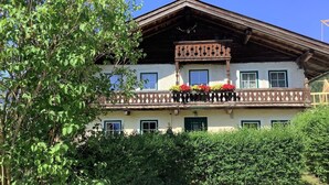 Un chalet traditionnel doté d’un balcon en bois, de nombreuses fenêtres et d’un jardin bien entretenu.