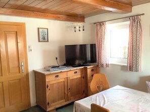 Une pièce comprenant un meuble en bois, une télévision, un lit et une fenêtre avec des rideaux.