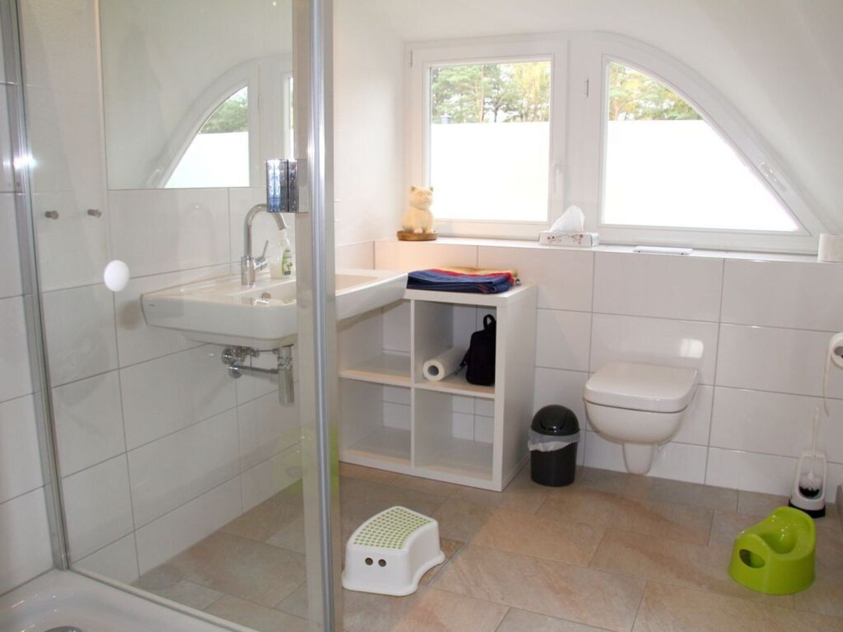 Une salle de bain moderne avec une douche à parois de verre, un lavabo, des toilettes et une petite fenêtre.