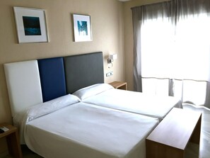 A hotel room with two beds, a nightstand, a wall-mounted lamp, and two framed pictures. - Apartment in Costa del Sol With Garden (Benalmádena)