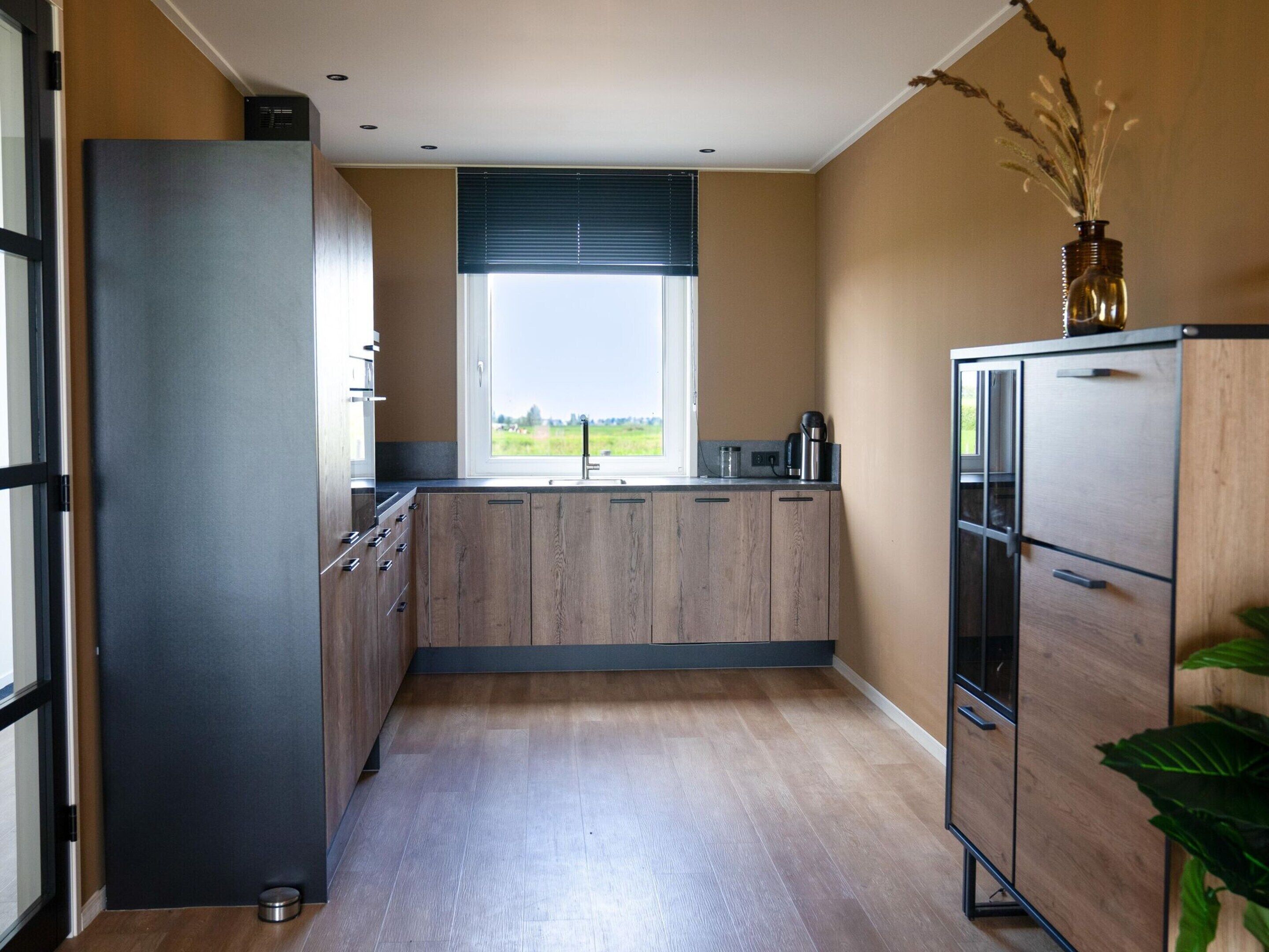 Een moderne keuken met een inbouwkoelkast, een gootsteen en een raam met uitzicht op de omgeving.