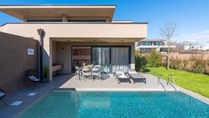 A modern building with a swimming pool, outdoor seating, and a covered patio area. - Family Apartment in Novigrad (Brtonigla)