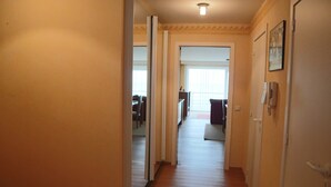 A hallway with wooden flooring leading to a room with a bed and a window. - Seafront Apartment in Nieuwpoort Marina (Nieuwpoort)