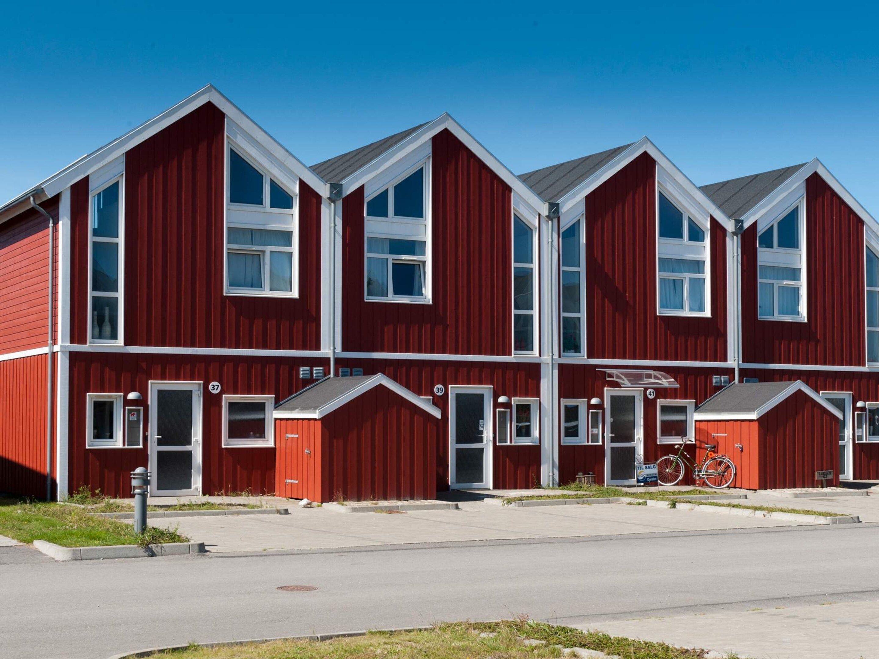 A red multi-story building with white trim, numbered doors, and large windows.
