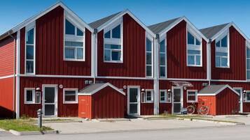 A red multi-story building with white trim, numbered doors, and large windows.