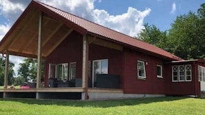 Ein rotes Gebäude mit einer Veranda und einem Rasen.