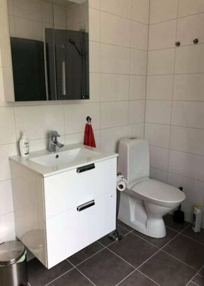 A modern bathroom with a white sink, mirror, and toilet.