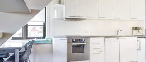 Cozinha moderna com armários brancos, forno embutido e máquina de café.