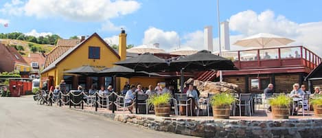Een restaurant met terras, stenen muren en een vlag.