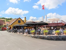 En restaurant med udendørs siddepladser, stenvægge og et flag.