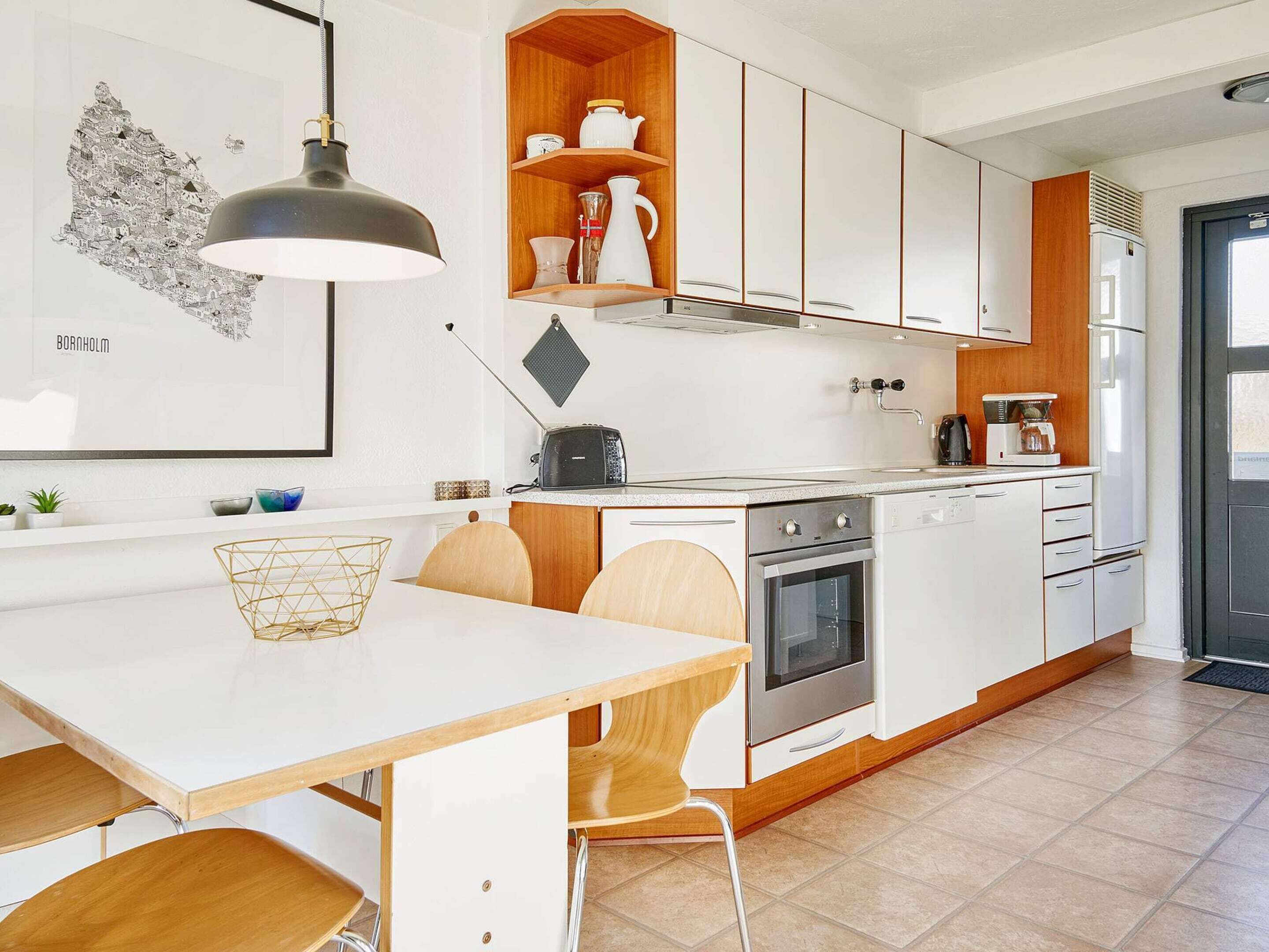 Una cocina moderna con armarios blancos, encimera de madera y una zona de comedor con una mesa blanca y sillas de madera.
