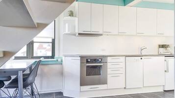 Una cucina moderna con mobili bianchi, forno integrato e macchina per il caffè.