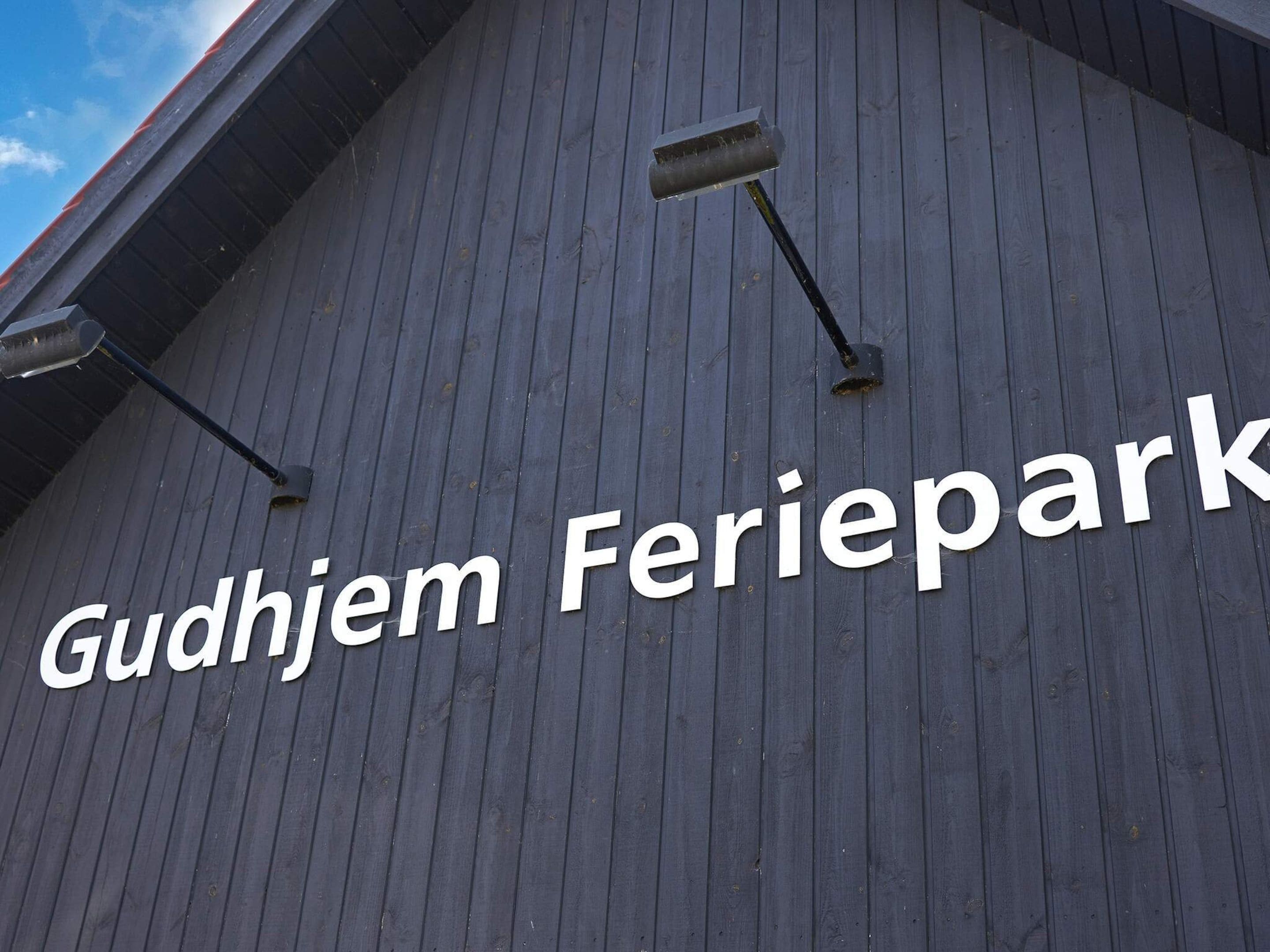 A building facade with the text "Gudhjem Feriepark" and three security cameras mounted on the wall.
