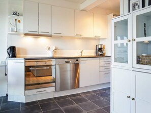 A modern kitchen with white cabinets, a Bosch dishwasher, an oven, and a coffee maker. - 5 Person Holiday Park Home in Gudhjem (Gudhjem)