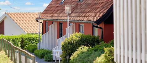 A narrow pathway leading to a row of houses with red roofs and white railings.