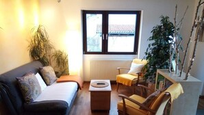 Een woonkamer met een bank, fauteuils, een salontafel en een groot raam met uitzicht.