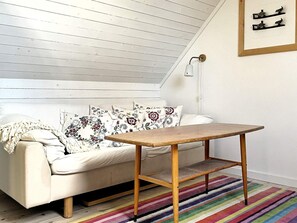 Una habitación acogedora con un sofá blanco, una mesa de madera y un tapete a rayas de colores.