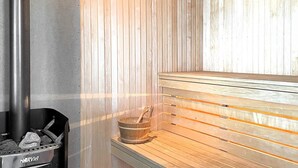 A sauna with a bench, a bucket, and a charcoal container. - 4 Star Holiday Home in Linkoping (Linkoping)