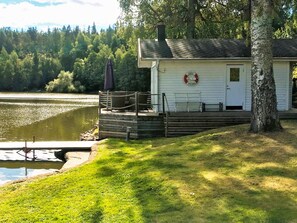 A lakeside cabin with a dock, a lifebuoy on the wall, and a bench. - 4 Star Holiday Home in Linkoping (Linkoping)