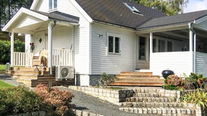 A two-story house with a porch, a covered front porch area, and a small garden with a stone wall. - 4 Star Holiday Home in Linkoping (Linkoping)