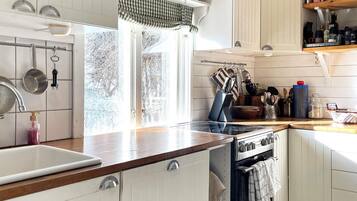 A kitchen with white cabinets, a stove, a sink, and various kitchen utensils.