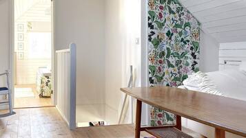 A bedroom with a wooden bed, a colorful striped rug, and a floral-patterned wall.