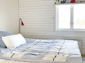 A bed with a striped pillow, a red lamp, and a window with blinds. - 4 Star Holiday Home in Linkoping (Linkoping)