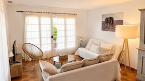 Una sala de estar con un sofá, una silla, una mesa de centro, una lámpara y un cuadro en la pared.