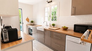 Cocina moderna con microondas, pileta y encimera de madera.